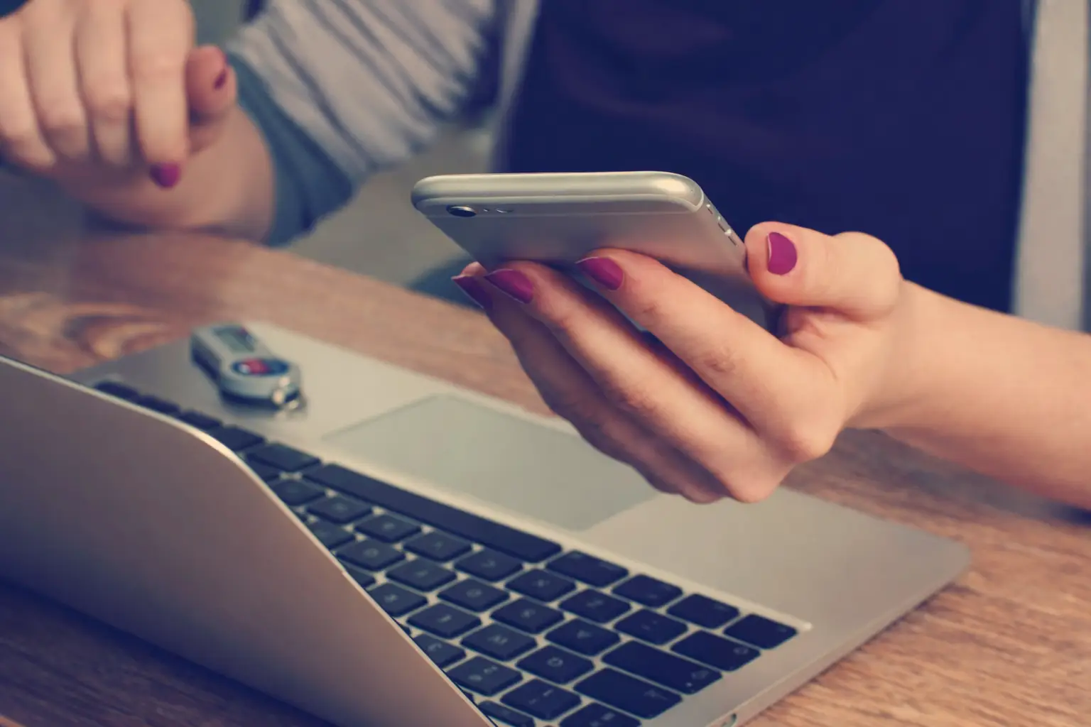A person holding a smartphone reaching out to connect to BASE Data Advisory for a consultation on fractional data strategy solutions for start-up to scale-up companies.